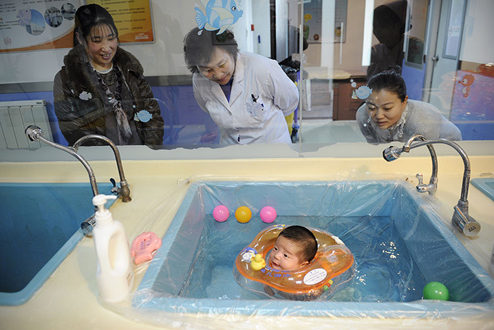 24 hours in pictures: A baby swimming in a basin with a water wing