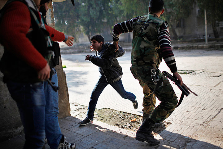 20 Photos: A Free Syrian Army fighter pulls a boy away from sniper fire in Aleppo