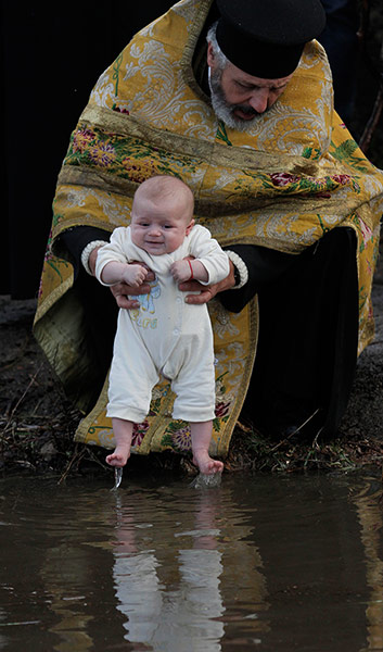 Epiphany Day: An Orthodox priest baptizes newborn baby 