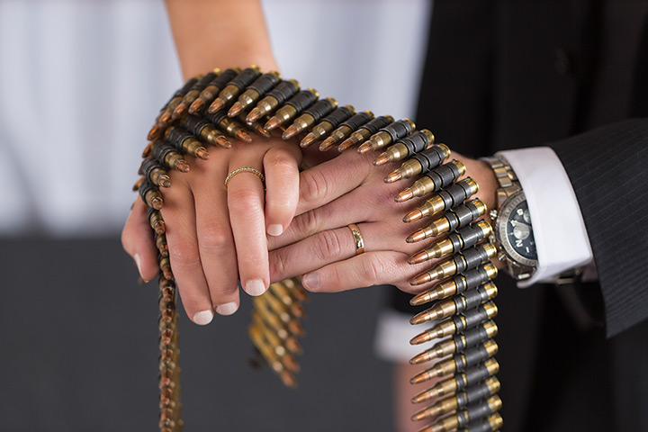 Shotgun weddings: A couple shows their wedding rings with group of shell casings
