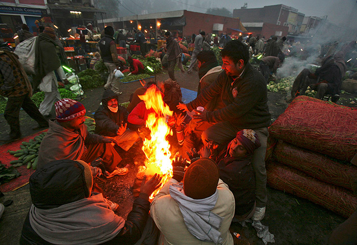 Cold weather in India: People warm themselves by a fire at a vegetable wholesale market