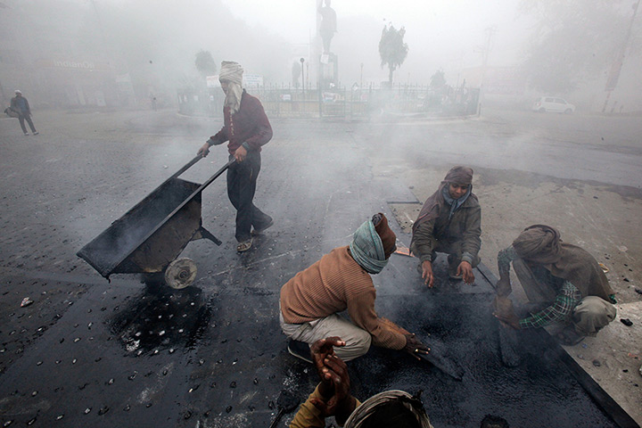 Cold weather in India: Labourers repair a road surrounded by fog  in Allahabad