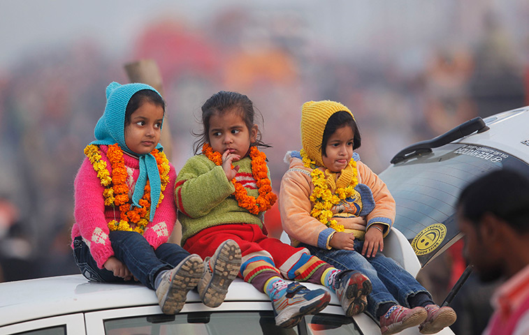 Cold weather in India: Children watch a religious procession while wrapped in woollen clothes
