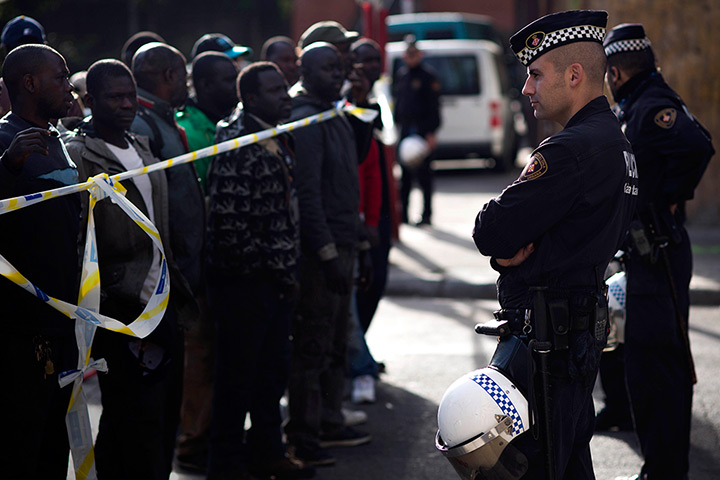 24 hours: Barcelona, Spain: Police officers cordon off a street to hold immigrants
