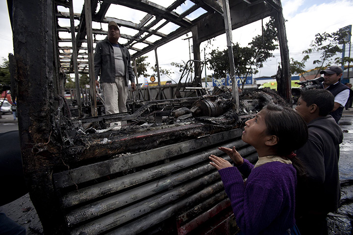 24 hours: Guatemala City, Guatemala: Children look at a burnt public bus