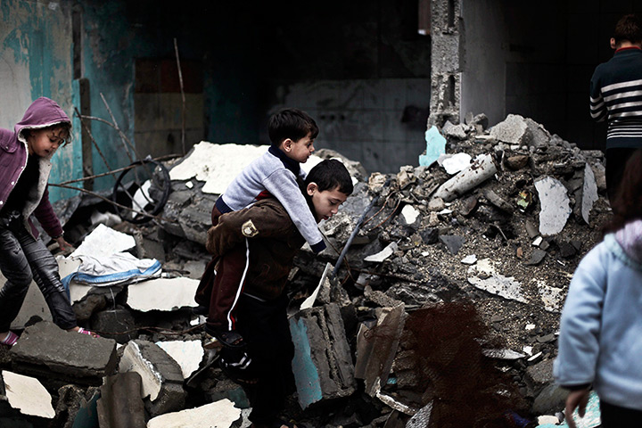 24 hours in pictures: A Palestinian child holds his brother as they walk over rubble 