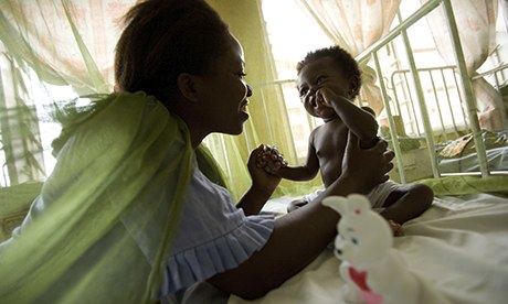 A woman attends her baby girl who sits under a mosquito net