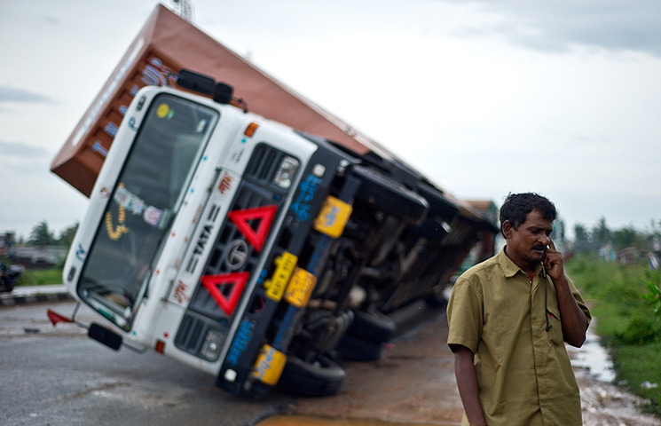 Cyclone Phailin: A truck driver Jairam Yadav speaks on his mobile phone after his truck carr