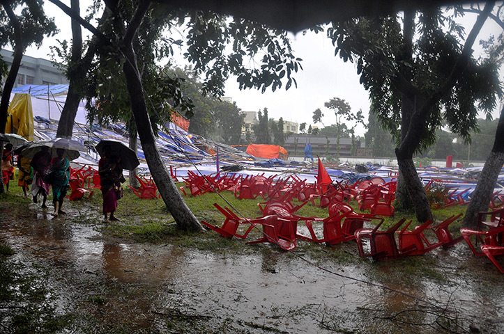 Cyclone Phailin: Women walk past a collapsed marquee and chairs set up for a Christian praye