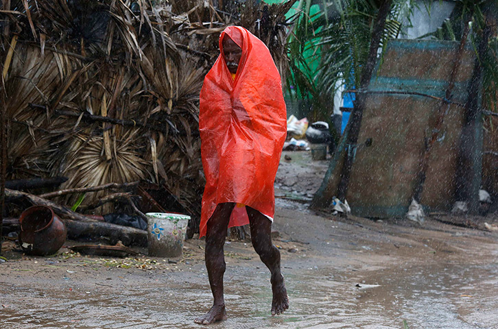 Cyclone Phailin: A man covers himself with a plastic sheet as he walks to a safer place in t