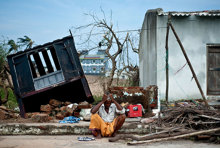 Cyclone Phailin damage: Bhagwan, a coconut-seller, sits in front of his destroyed shop in Gopalpur