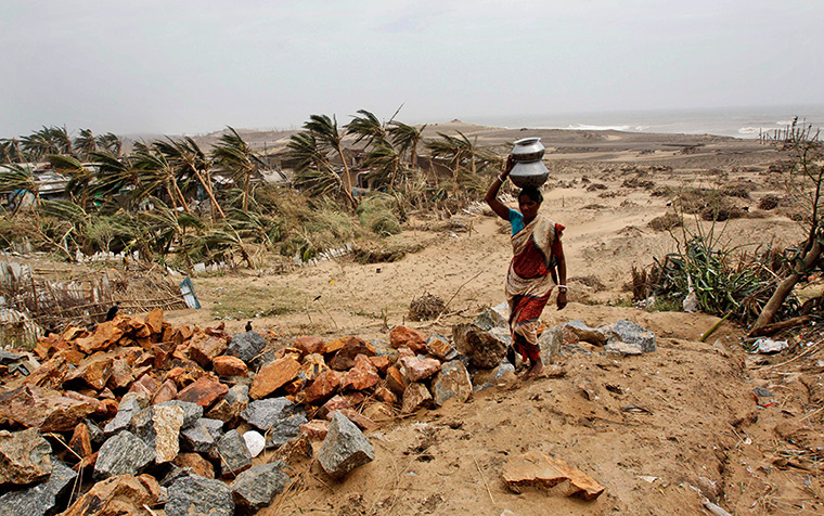 Cyclone Phailin damage: A villager carries drinking water on her head as she walks to the cyclone-h