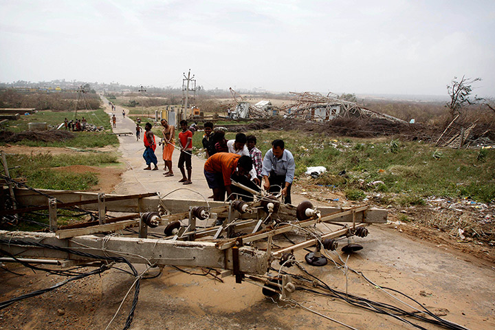 Cyclone Phailin damage: People try to remove an electric pole that was felled at Arjipalli village 