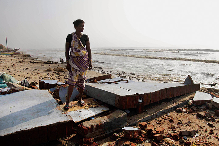 Cyclone Phailin damage: A woman stands amidst the debris of damaged houses in a cyclone affected vi