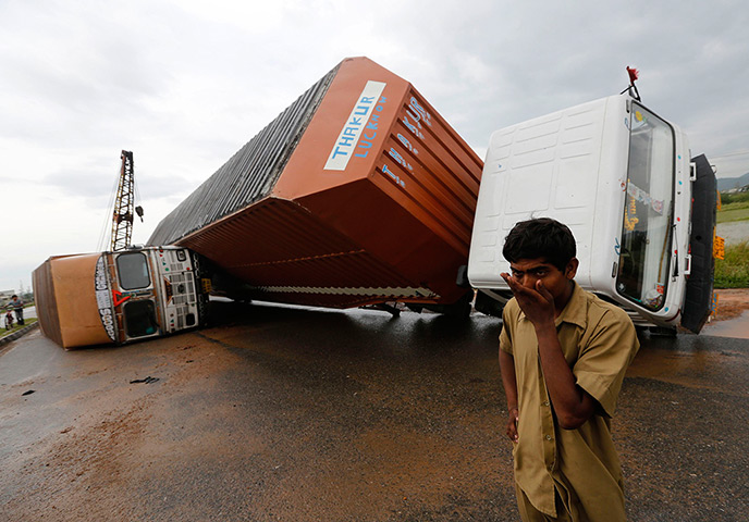 Cyclone Phailin damage: A man stands next to overturned trucks near Girisola town 