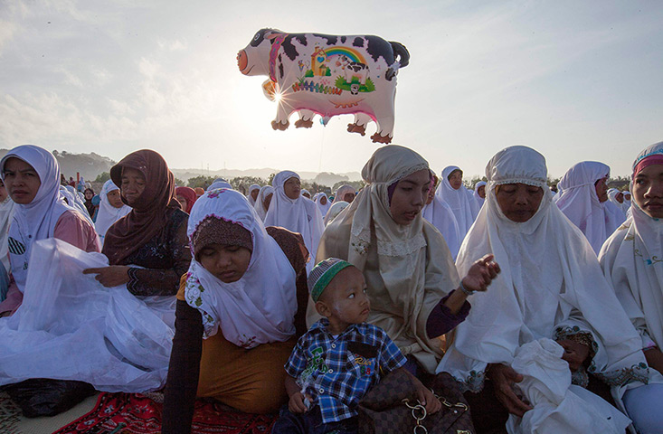 Eid al-Adha: A cow balloon flies as women and children attend an Eid al-Adha mass prayer