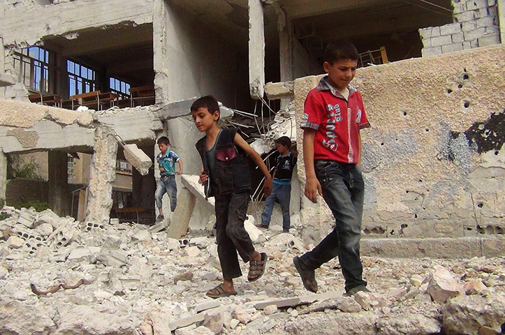 Syria schoolchildren: Children walk among debris from a damaged school building in the Damascus s