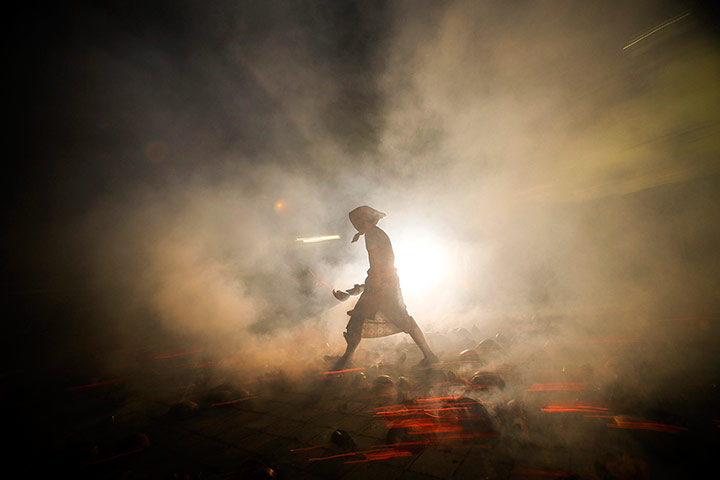 Weekend in pictures: Bali, Indonesia: A man walks among blazing coconut husks