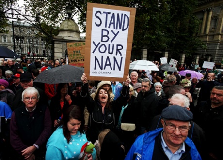 A woman holds a sign during a protest by pensioners, outside Leinster House, Dublin, in reaction to Budget 2014.