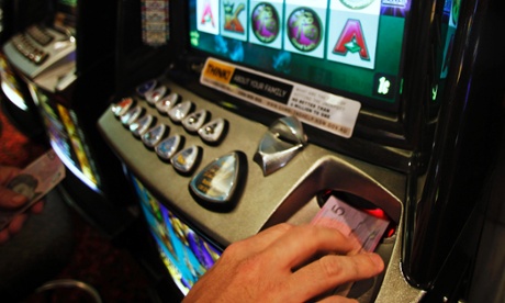 A man inserts a five Australian dollar note into a slot machine at Bowlers Club in Central Sydney.