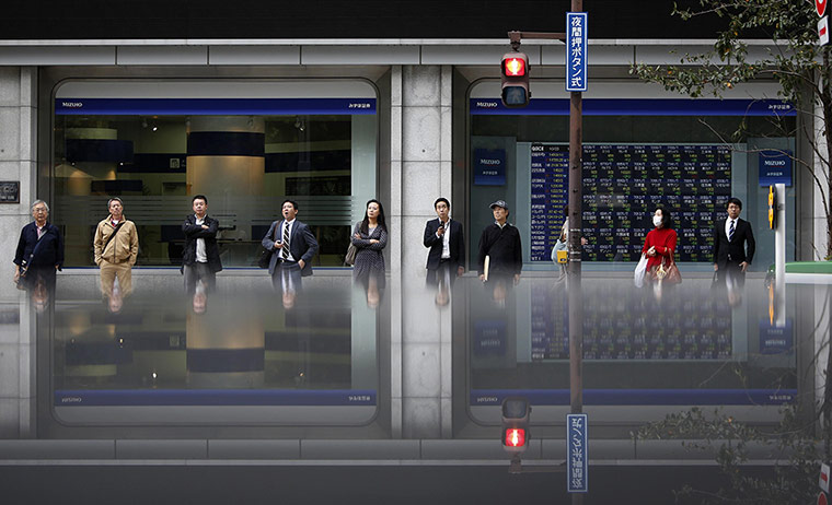 20 Photos: Pedestrians in front of an electronic board showing stock prices in Tokyo