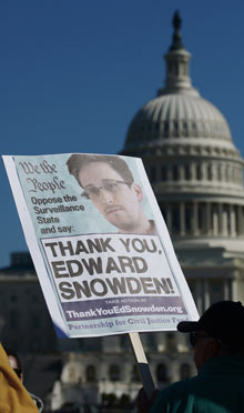 Demonstrators hold placards supporting Edward Snowden
