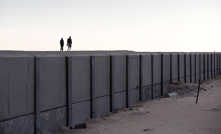 Weekend in pictures: Queens, New York, US: Two people walk on a beach in Belle Harbor which was raised with a steel-reinforced concrete wall after superstorm Sandy