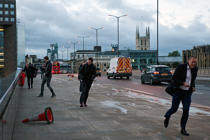 Storm damage: People crossing London Bridge struggle with heavy winds as the city is hit by the storm