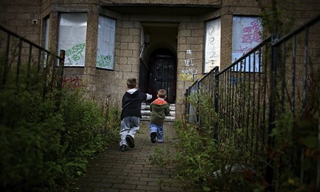 Two young boys play in front of boarded-up houses in Govan, Glasgow