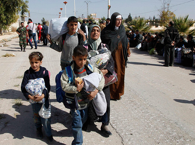 Syrian families carrying belongings