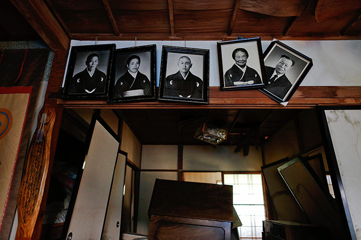 Fukushima: Portraits hang from the wall of an abandoned and damaged house