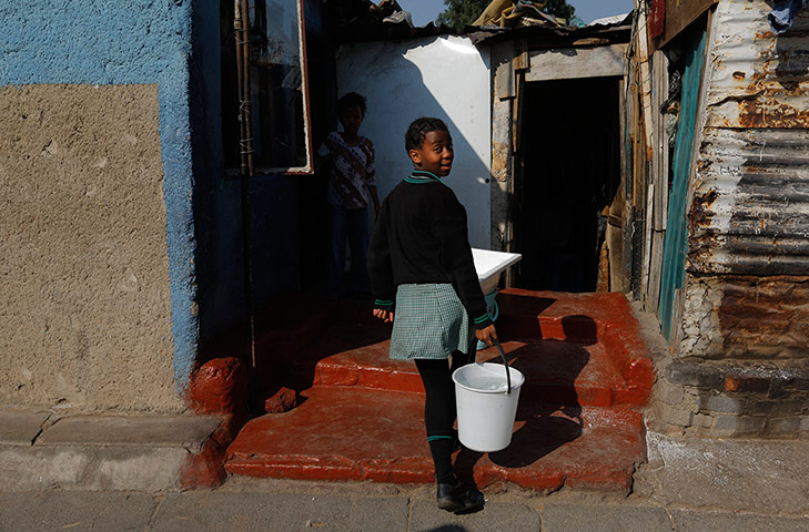 Alexandra Township: A girl carries a bucket of water to her family's shack