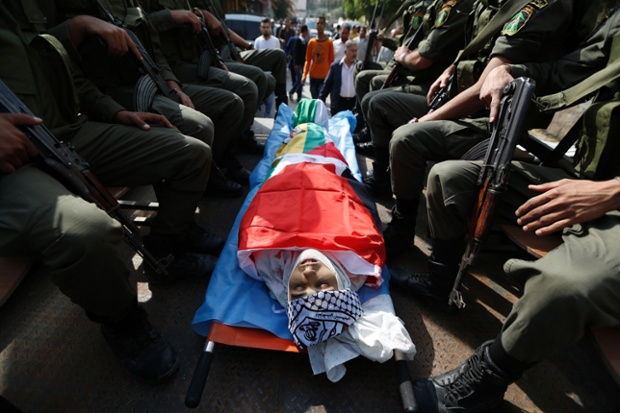 Members of the Palestinian security forces sit around the body of Ahmed Imad Yusef during his funeral in the West Bank village of Qabatiya, near Jenin.