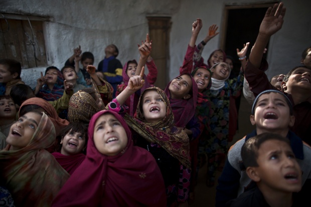 Afghan refugees and Pakistani schoolchildren sing during morning assembly, before starting their classes, on the outskirts of Islamabad, Pakistan.