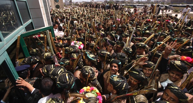 Grooms, wearing traditional costumes and carrying swords, try to enter a building for a mass wedding ceremony in Sana'a, Yemen.