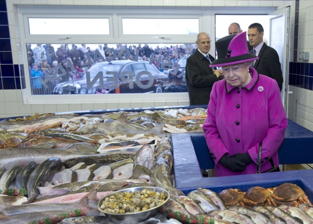 Queen Elizabeth II looks at fish during a visit to West Quay Fisheries, Newhaven Fish Market, East Sussex.