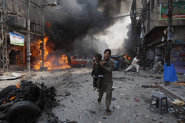 20 Photos: A man carrying a child rushes away from a bomb blast in Peshawar, Pakistan