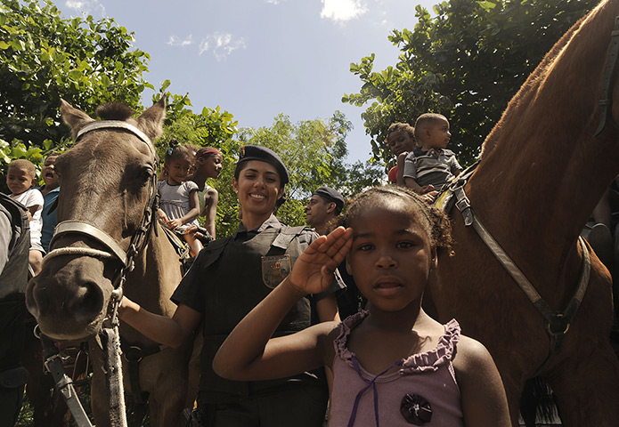 Favela clearance: A young child salutes next to a police officer i