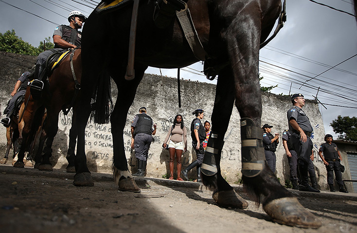 Favela clearances: Residents watch as military police on horseback patrol during a 'pacificati