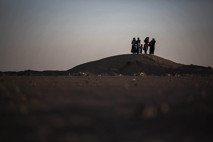 20 Photos: Syrian women stand on top of a small mound searching for a mobile phone signal
