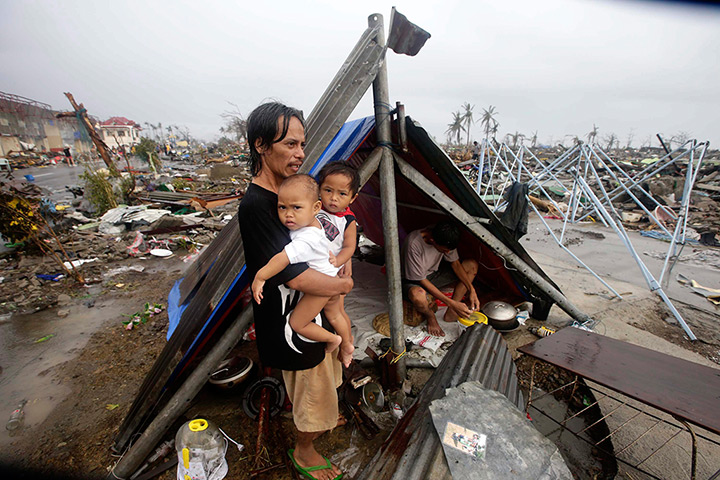 Typhoon hits Tacloban: a father waits with his children for food relief 