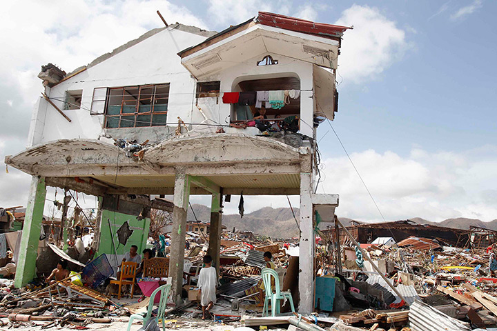 Typhoon hits Tacloban: survivors stand in their damaged house in Tacloban