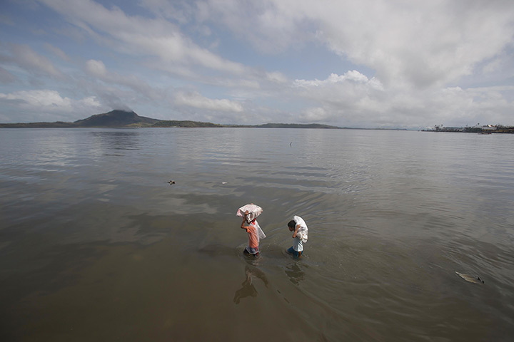 Typhoon hits Tacloban: residents carry relief goods along the bay 