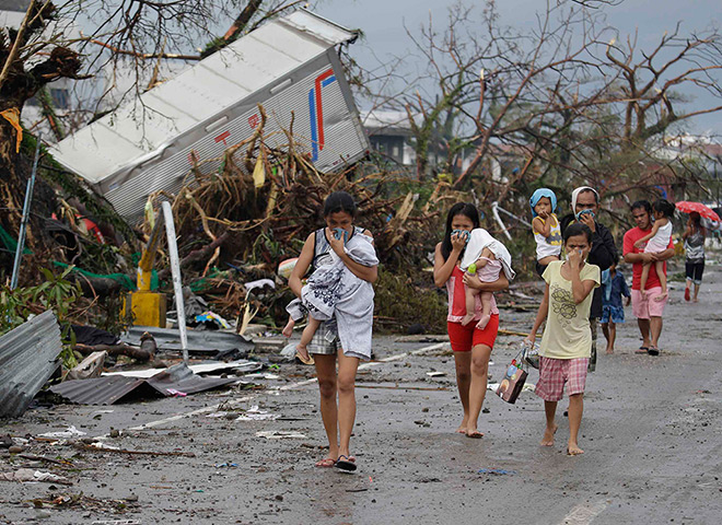 Typhoon hits Tacloban: residents cover their noses as they walk near dead bodies 