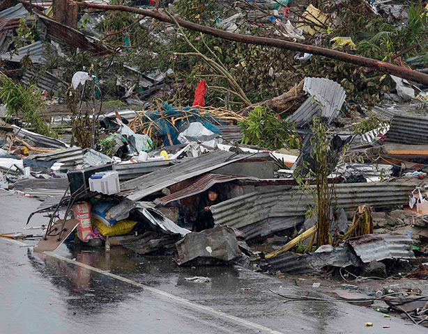 Typhoon hits Tacloban: a woman shelters in the remains of her damaged house 