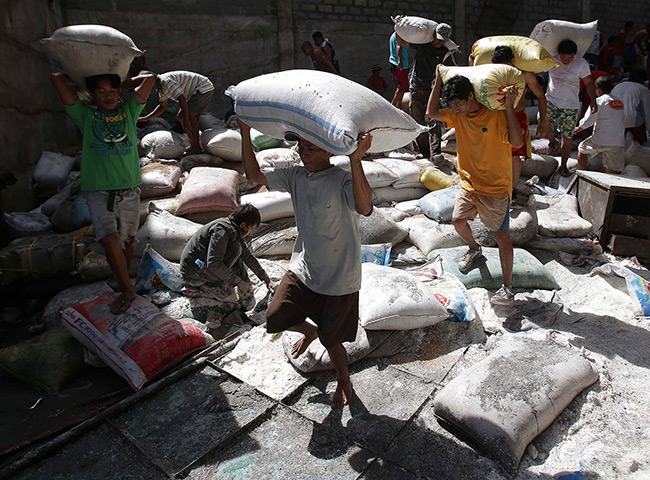 Tacloban survivors: Survivors bring bags of rice from a warehouse which they stormed due to foo