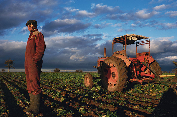 East Anglia - Weekend: man in red overalls stands in field with tractor in background