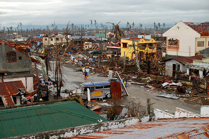 Typhoon Haiyan: A man carrying provisions walks through an area devastated by Typhoon Haiya