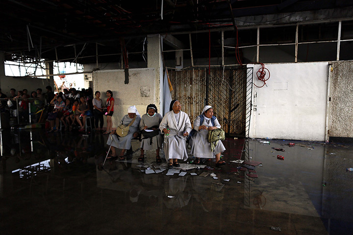 Typhoon Haiyan: Filipino nuns and other survivors wait for a military aircraft as they prep
