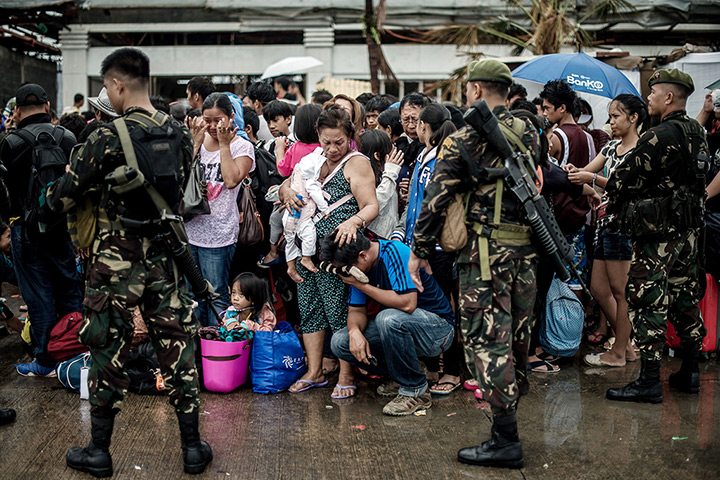Typhoon Haiyan: A woman holding a baby comforts a crying relative as a plane leaves the air